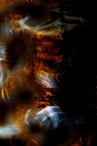 Abstract swirl of warm orange and gold bokeh lights against a dark background, resembling a kaleidoscope of sparks.